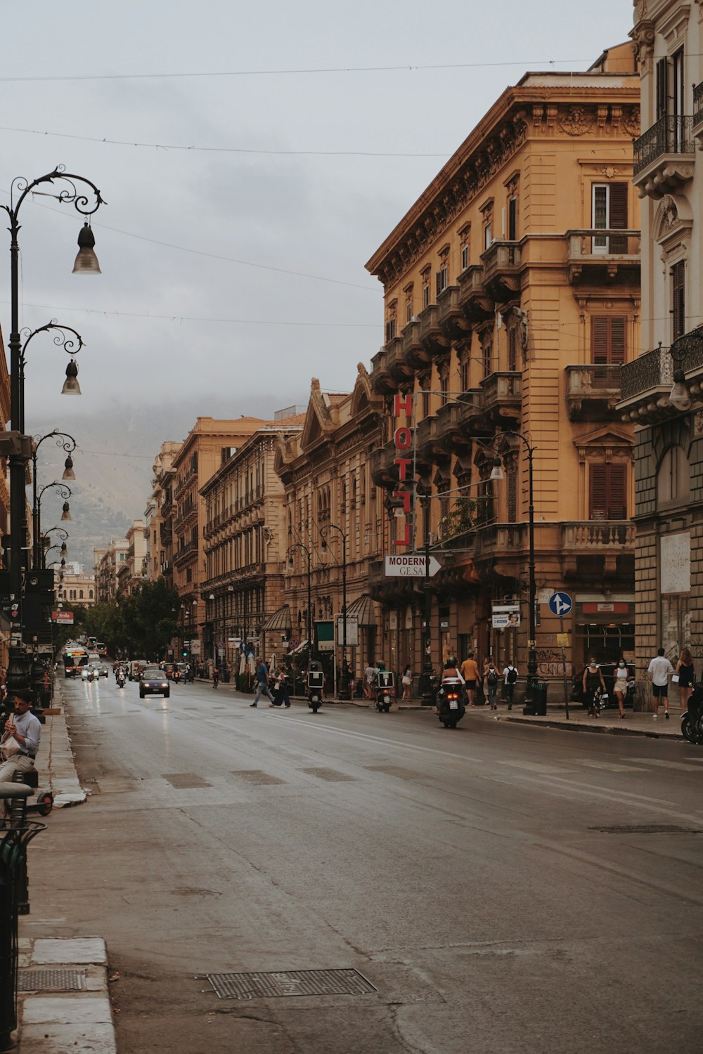 Personas caminando por la acera cerca de un edificio de concreto marrón durante el día