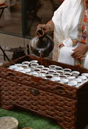 Artisan mixing natural ingredients for attar in a traditional copper pot
