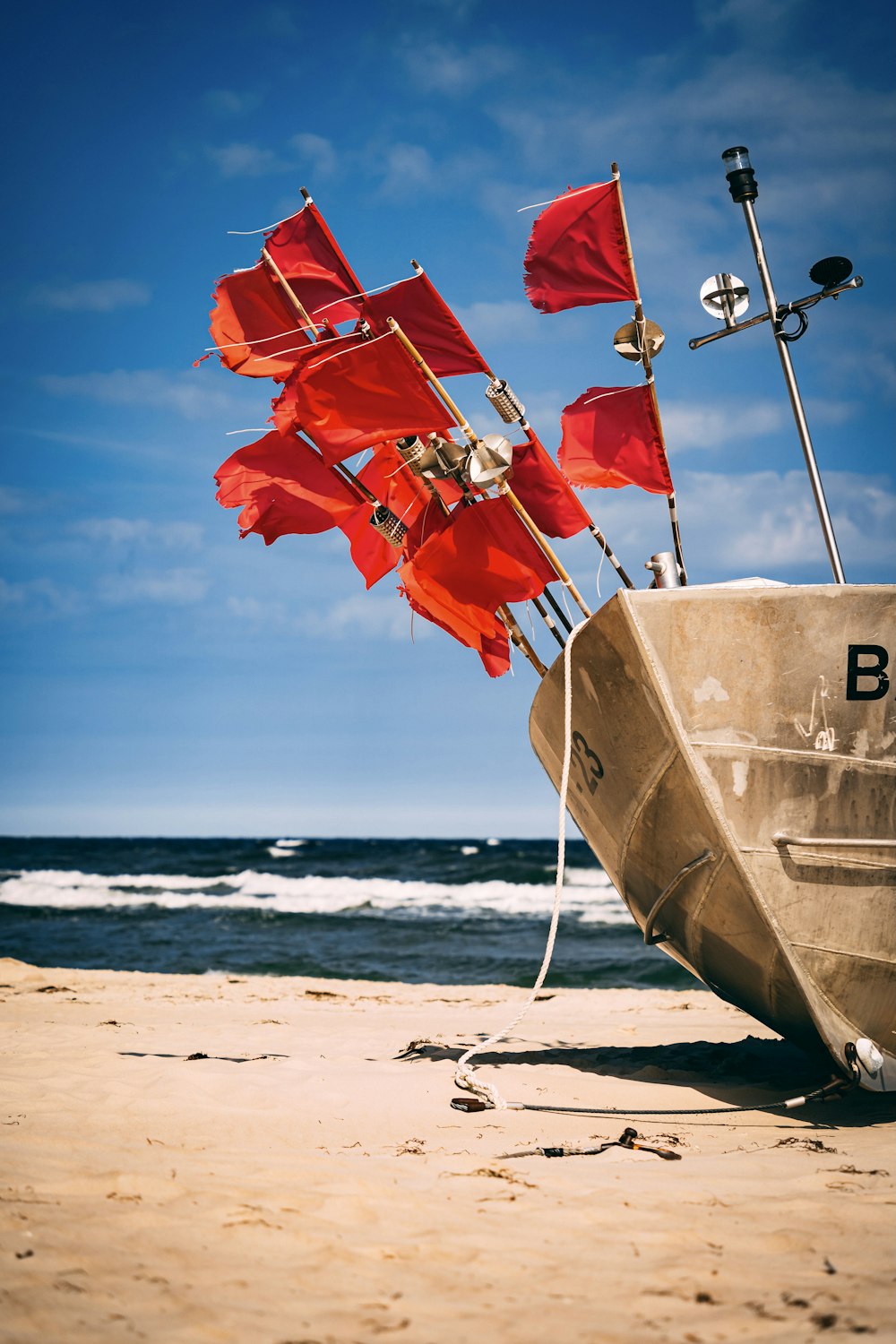 a boat on the beach with red flags sticking out of it