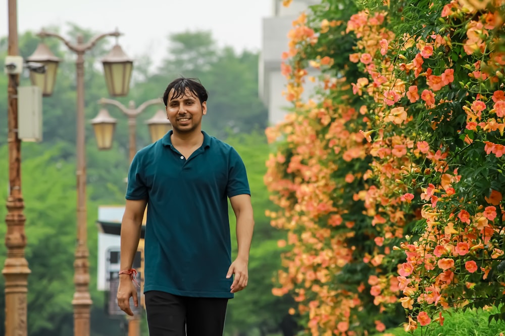 man in blue polo shirt standing near orange flowers during daytime