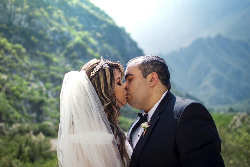 man in black suit kissing woman in white wedding dress