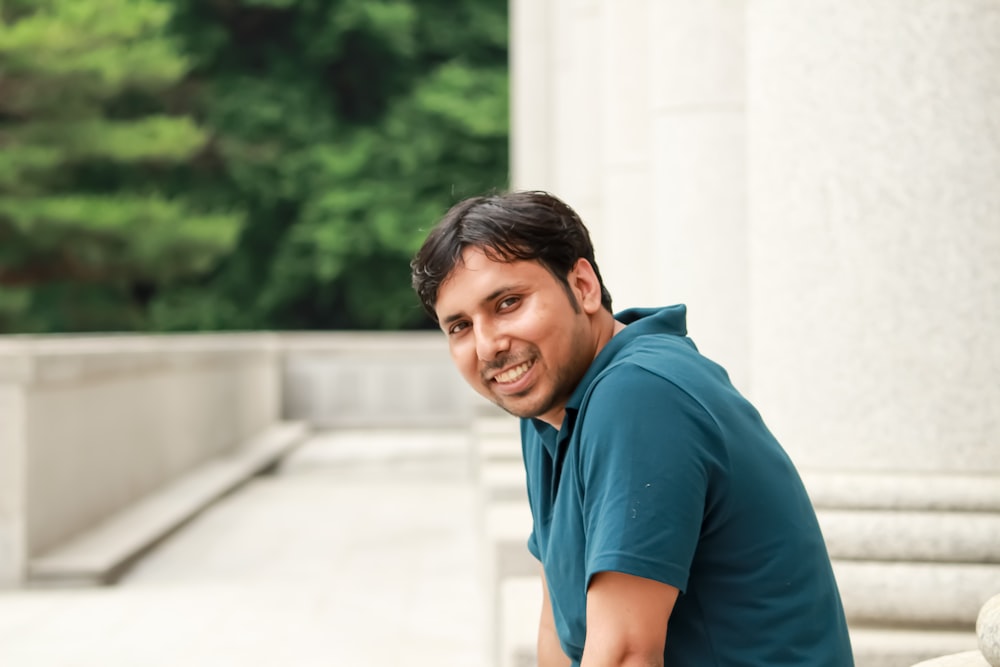 boy in blue polo shirt standing near white concrete wall during daytime