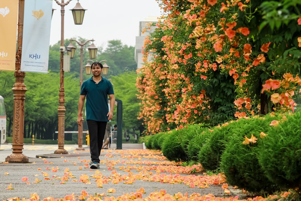 man in blue crew neck t-shirt standing on brown and white concrete pathway