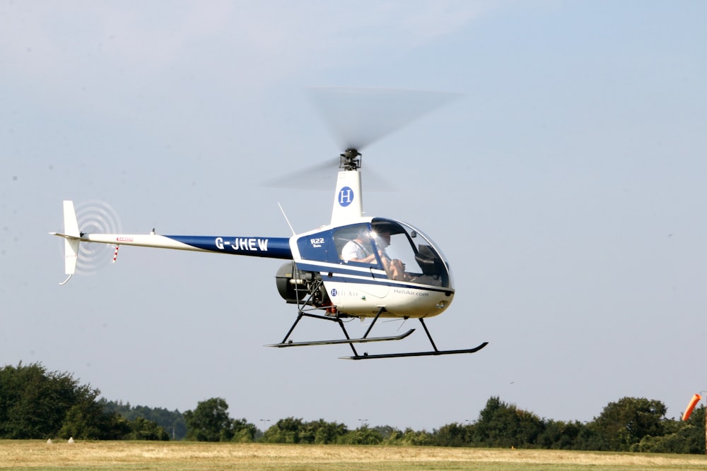 blue and white airplane flying over green grass field during daytime