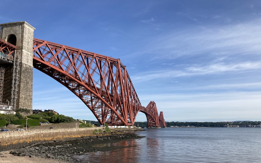 red metal bridge over the river under blue sky during daytime
