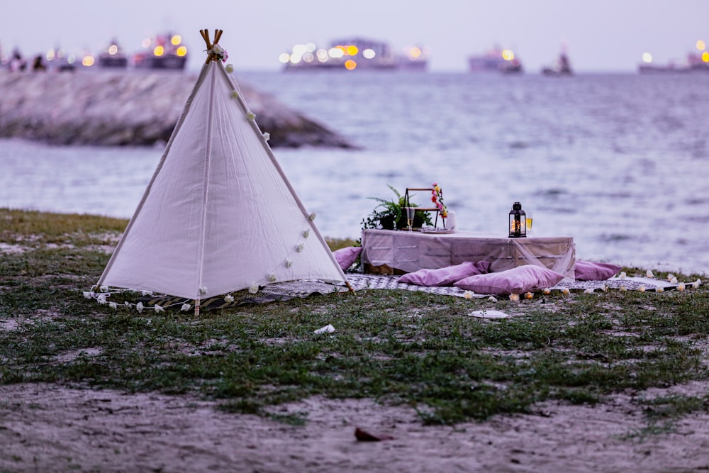 man and woman sitting on white tent near body of water during daytime