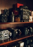 A collection of refurbished cameras and lenses neatly displayed on shelves.