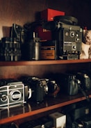 A collection of refurbished cameras and lenses neatly displayed on shelves.