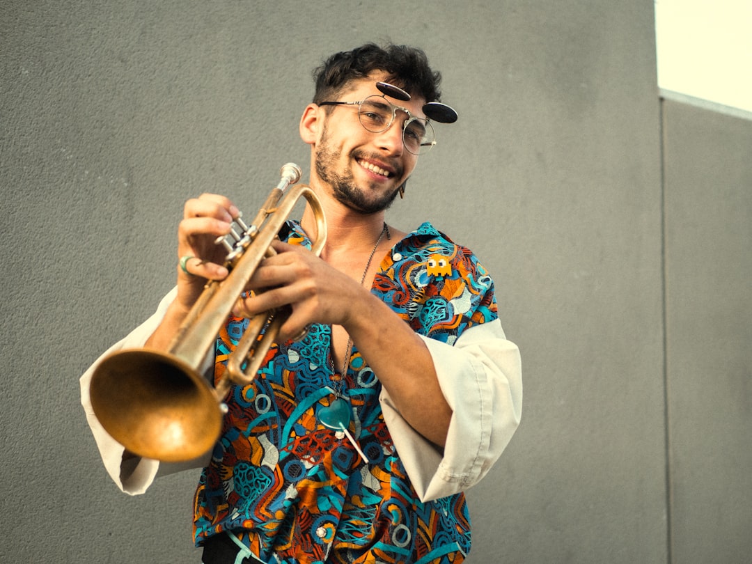 man in blue and red floral dress shirt playing trumpet