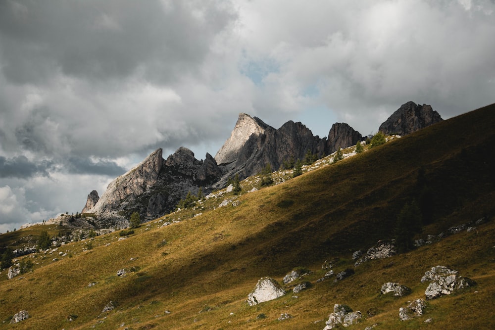 green grass field near mountain under cloudy sky during daytime