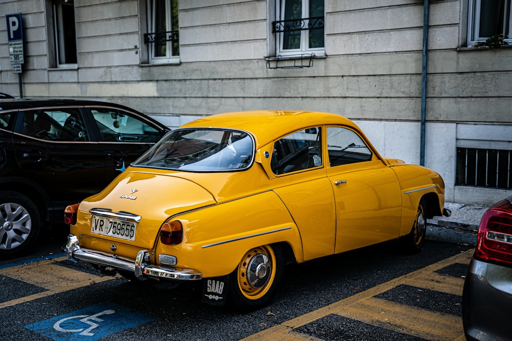 yellow volkswagen beetle parked beside white concrete building during daytime