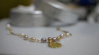 Softly lit close-up of elegant rose gold and pearl bracelets resting on a blush pink silk fabric.