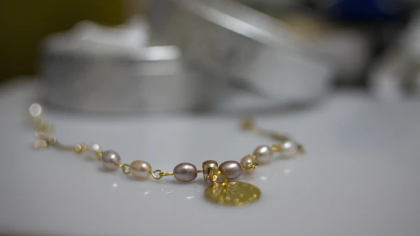 A sleek bracelet with polished gold links showcased on soft, warm-toned fabric.