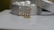 An elegant, decorative bracelet with pearls and a gold charm is draped over an ornate silver box, which has a floral pattern. The box lid is slightly ajar, revealing a soft, white interior.