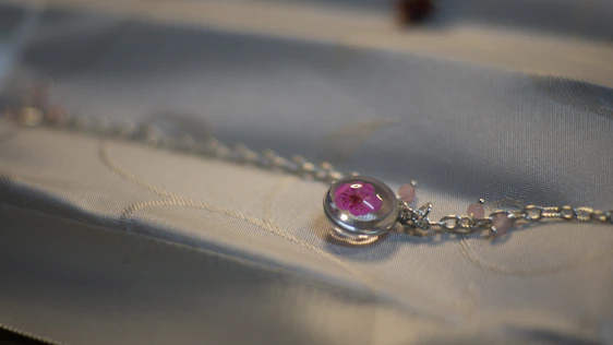 Close-up of a delicate rose gold necklace resting on soft blush pink fabric, highlighting intricate chain details and luminous craftsmanship.