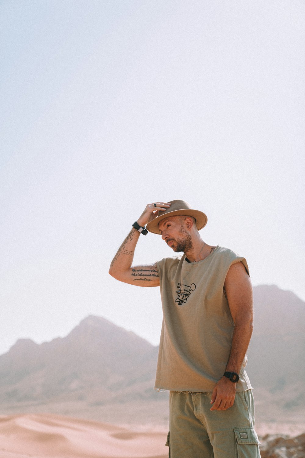 man in gray tank top and brown hat standing on top of mountain during daytime