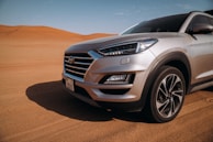 A luxury desert safari vehicle parked near golden dunes under a clear blue sky.