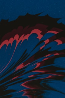 An abstract design featuring fluid, swirling shapes in dark red and black. The background is a textured deep blue, creating a dynamic contrast with the lighter elements that resemble splashes or waves.