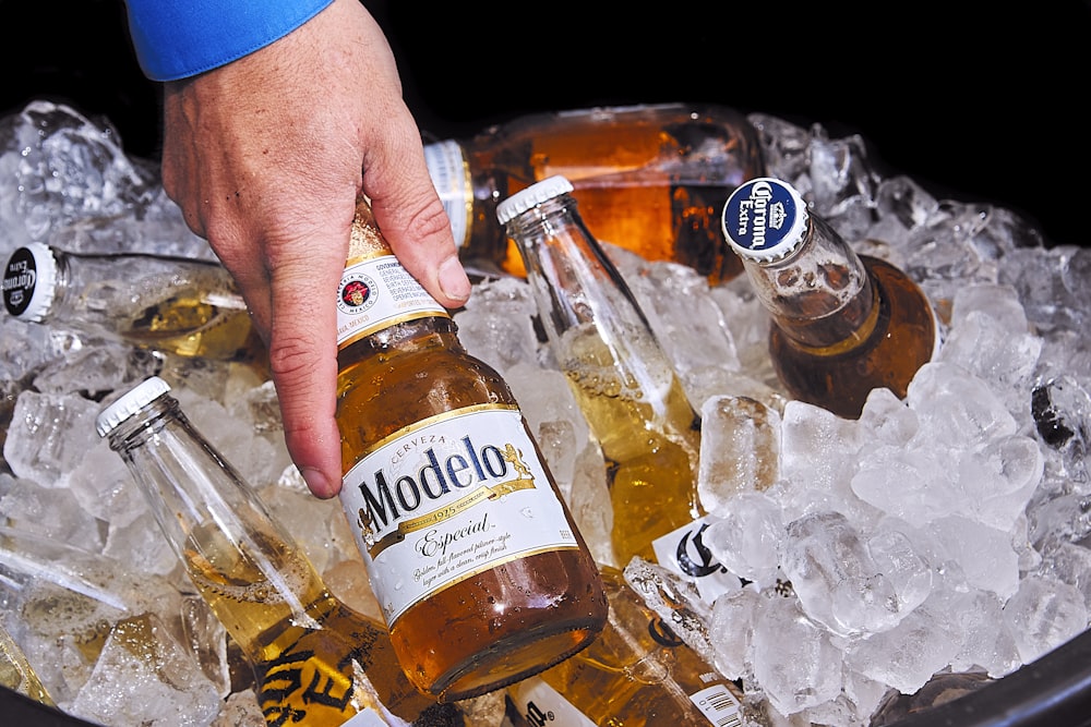 person holding brown glass bottle