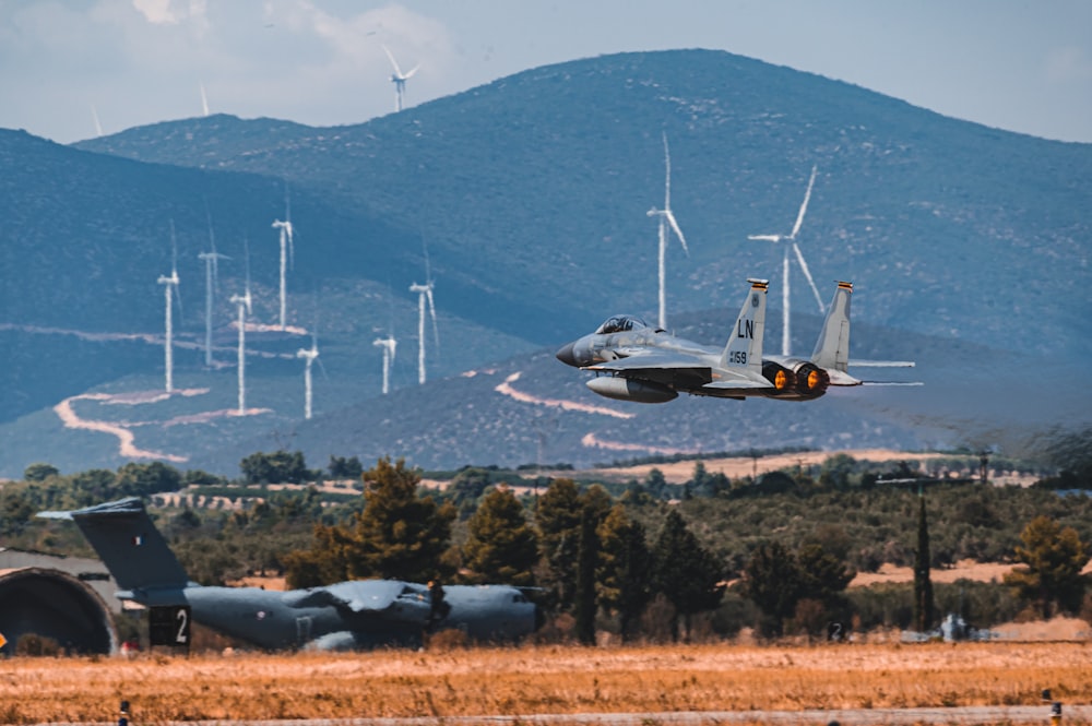 white and black fighter plane flying over green trees during daytime