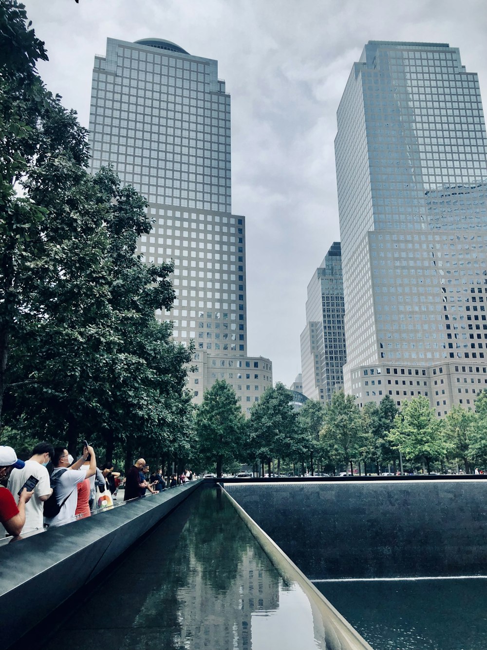 people walking on gray concrete bridge near high rise buildings during daytime