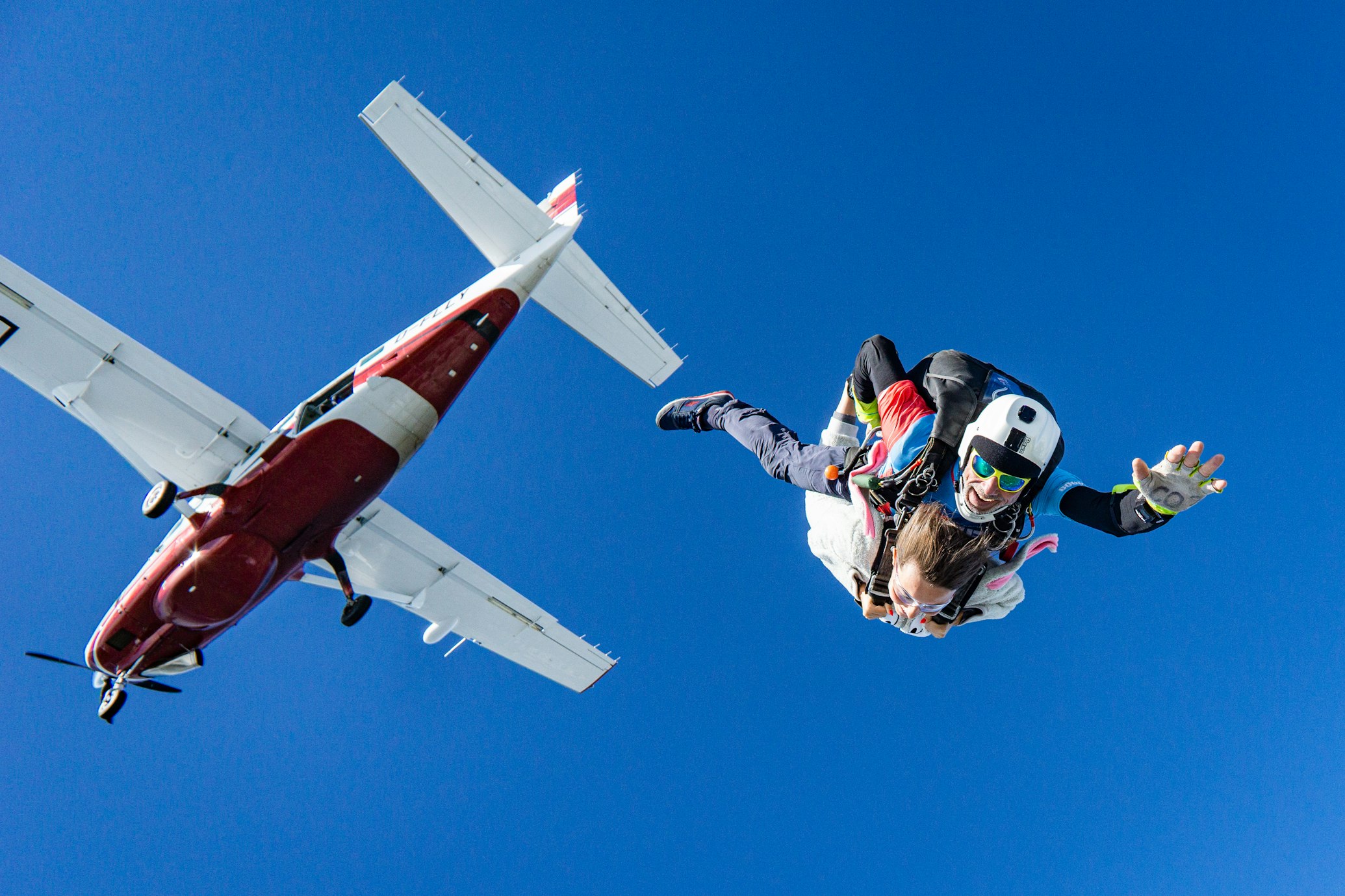 2 people skydiving off of a red airplane
