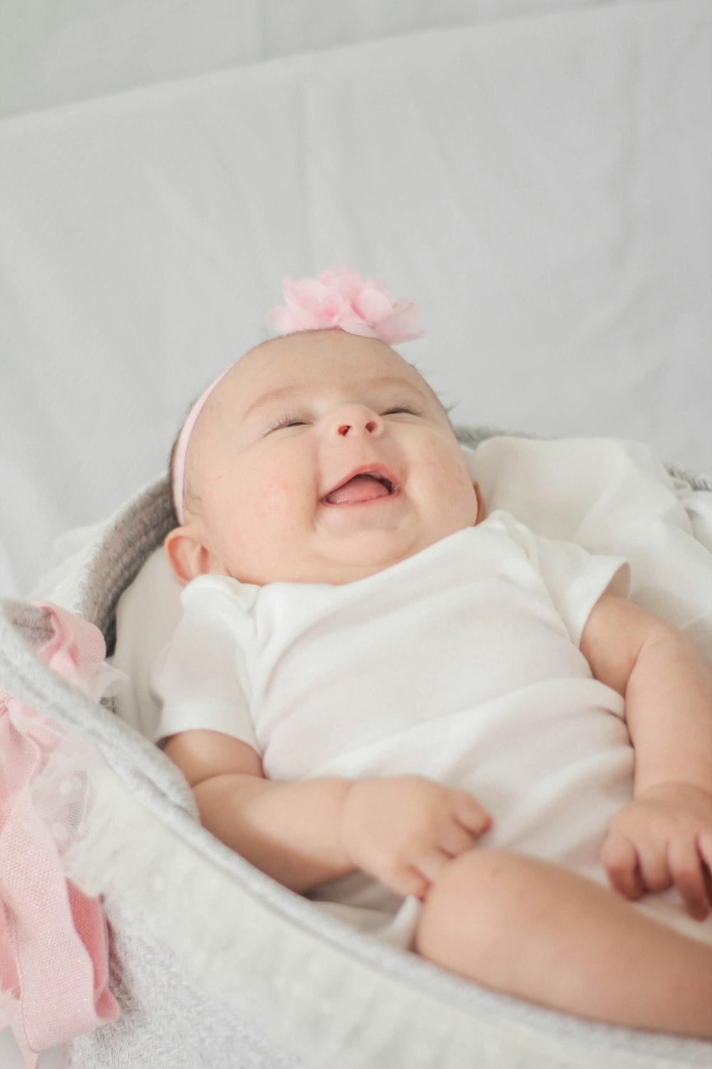 baby in white shirt lying on white textile