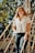 woman in white button up shirt and blue denim jeans sitting on brown wooden bridge during