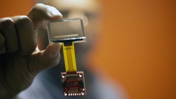 Close-up of a power amplifier MMIC chip held between fingers.
