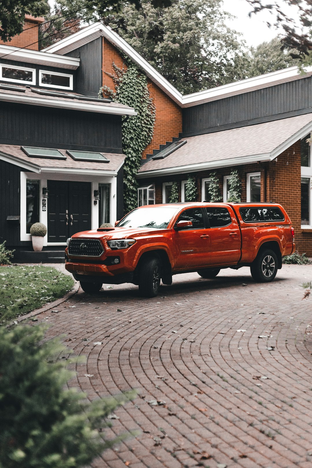 orange suv parked beside brown brick house