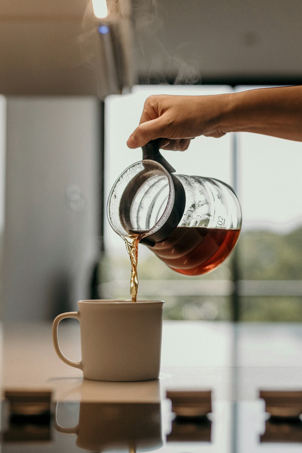 person pouring tea on white ceramic mug