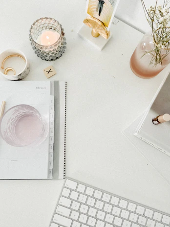 Calm, minimalist workspace with crystals and a journal beside a glowing candle.