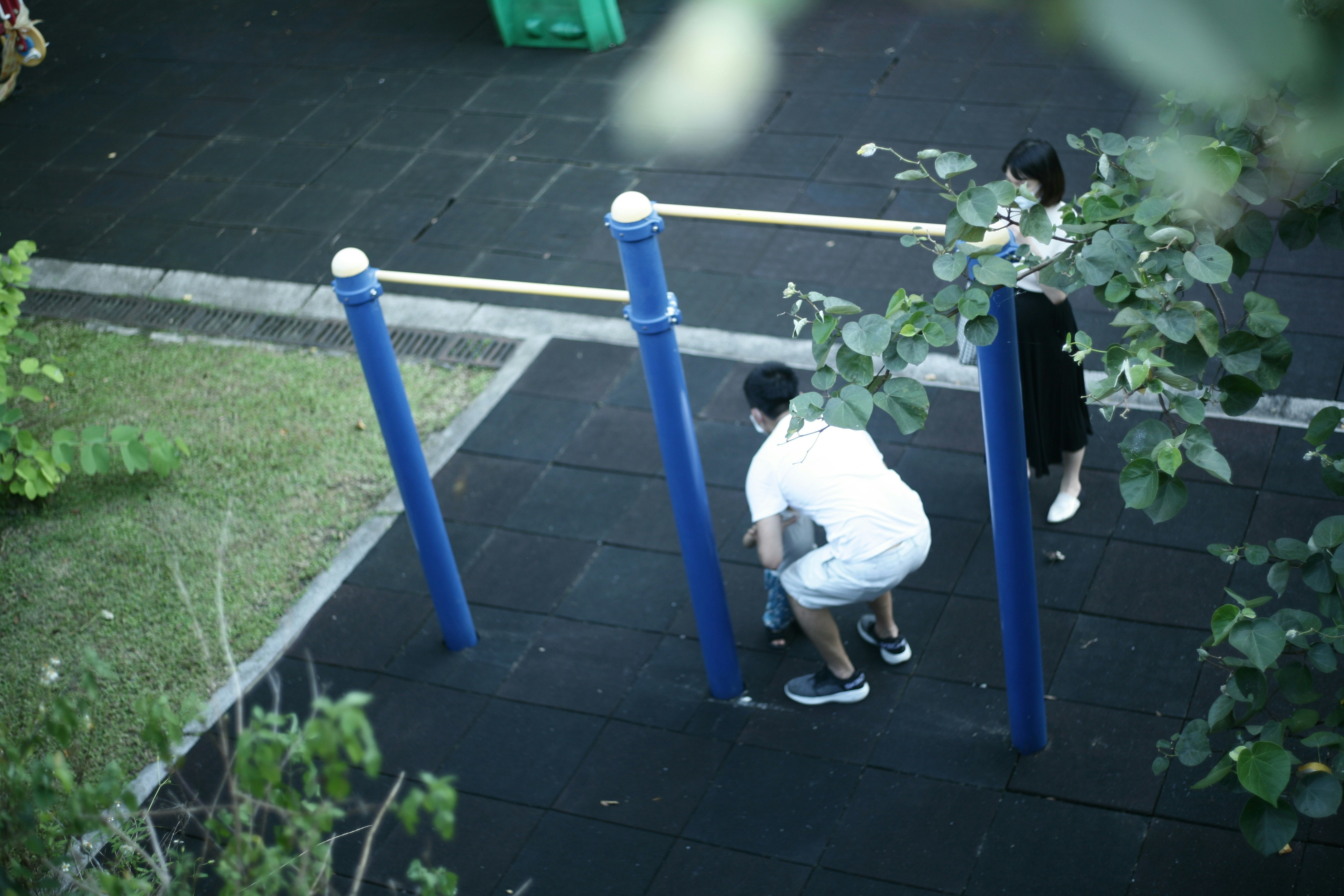 man in white t-shirt and blue shorts sitting on blue metal bar