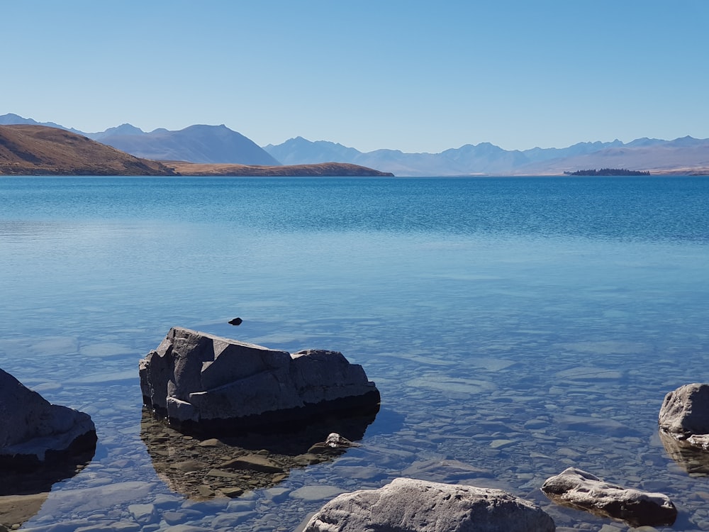 blue sea near mountain under blue sky during daytime