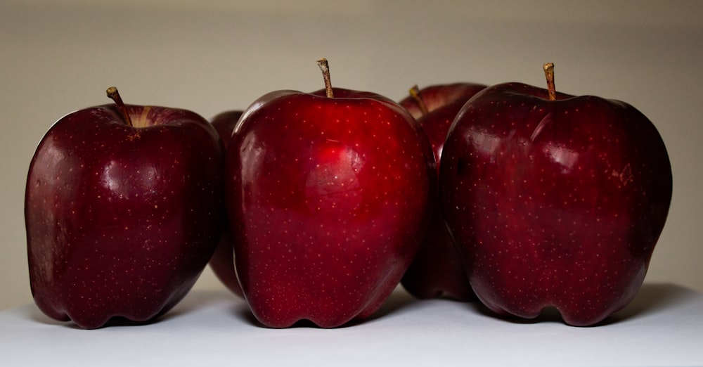 3 red apples on white surface