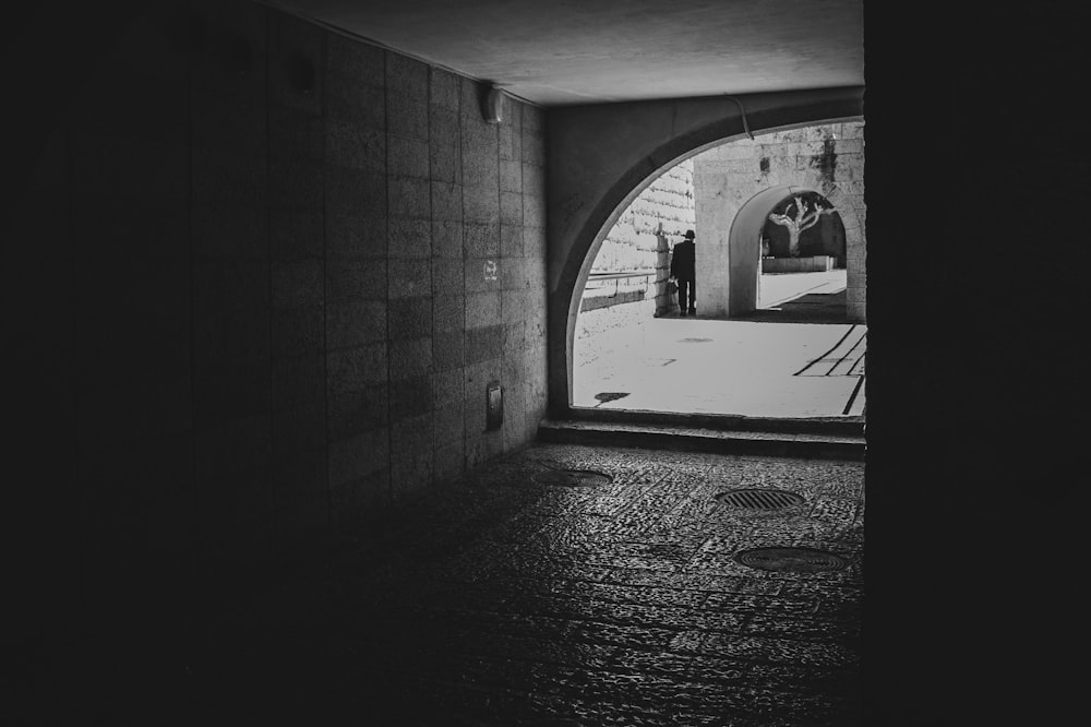 grayscale photo of person walking on hallway