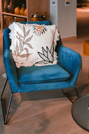 white and black floral throw pillow on blue sofa chair