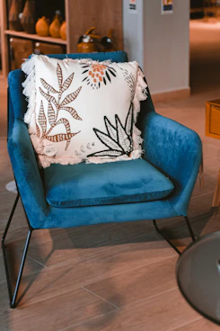white and black floral throw pillow on blue sofa chair