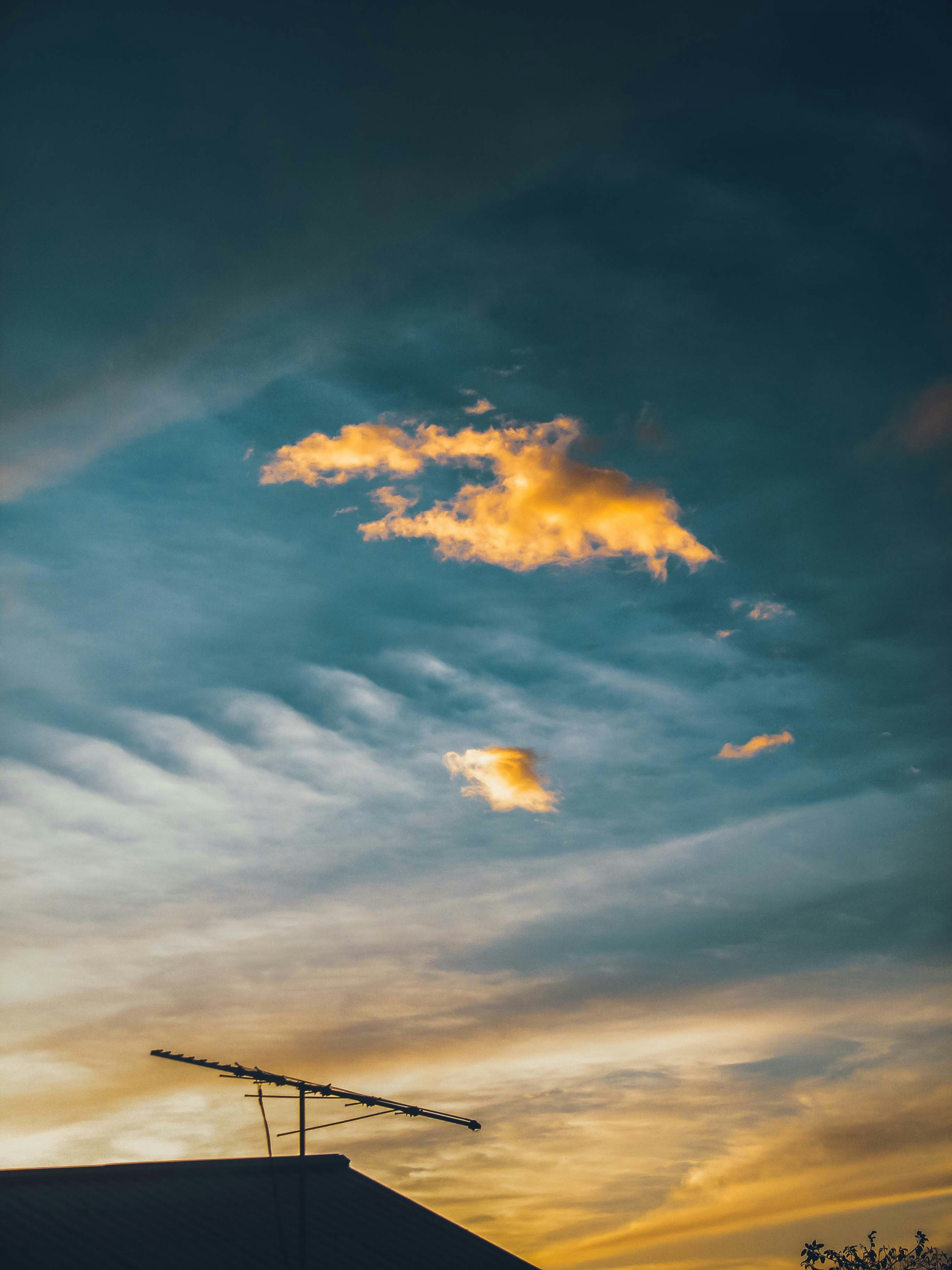 Dramatic twilight sky over a city rooftop with golden lights and deep blue clouds