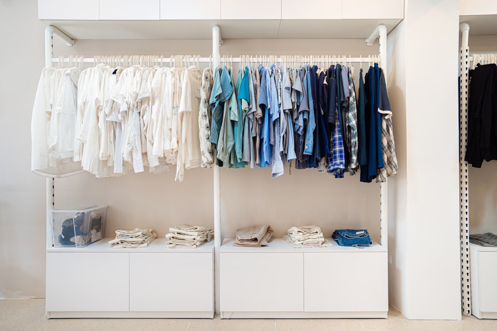 camisas blancas y azules colgadas en un armario de madera blanco