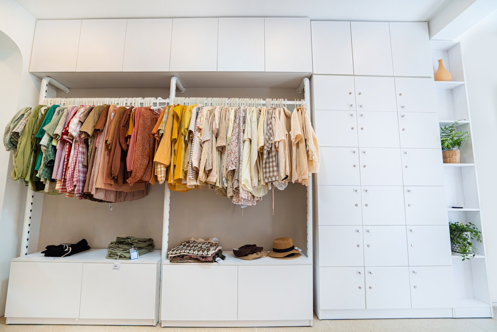 orange and yellow clothes hanged on white wooden cabinet