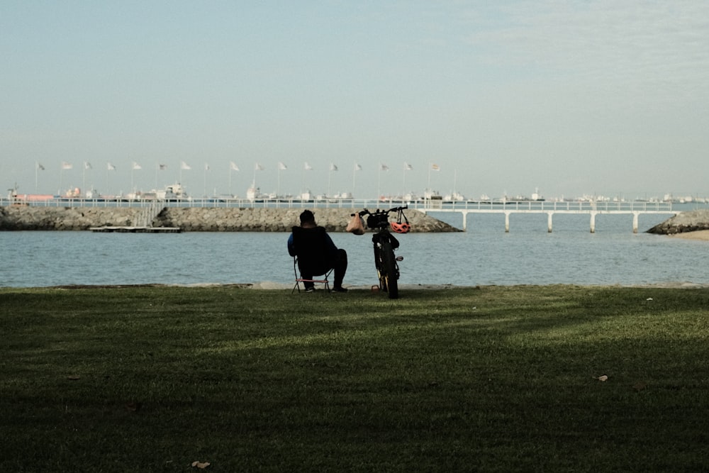 people walking on green grass field near body of water during daytime