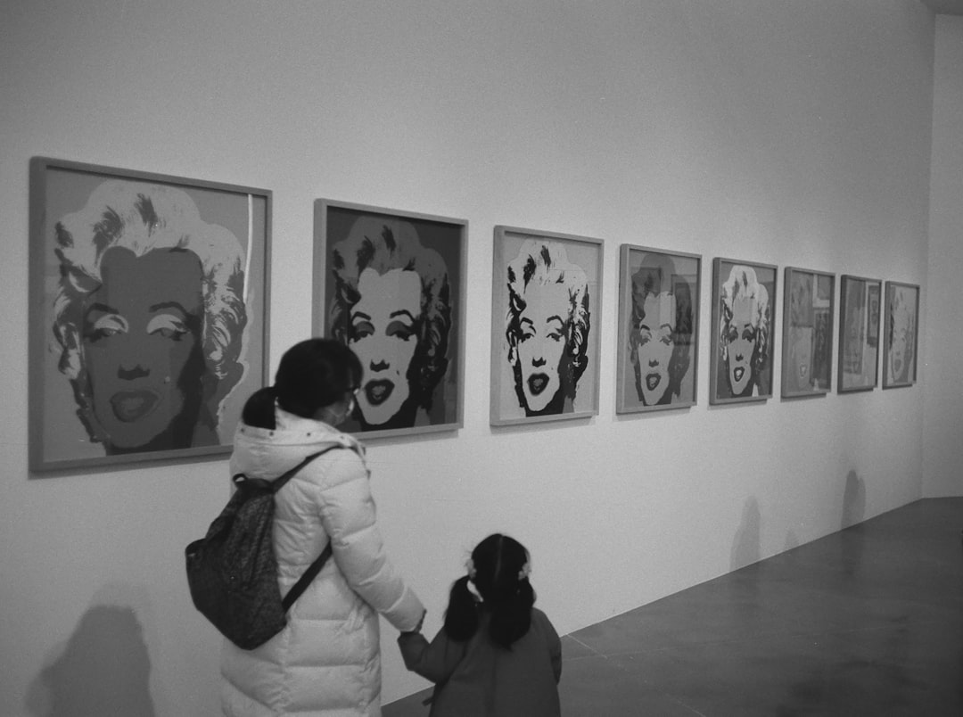 woman in white long sleeve shirt standing in front of wall with paintings