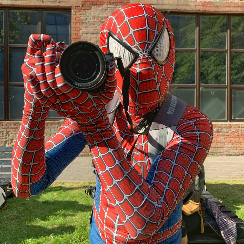 person in spider man costume holding black camera