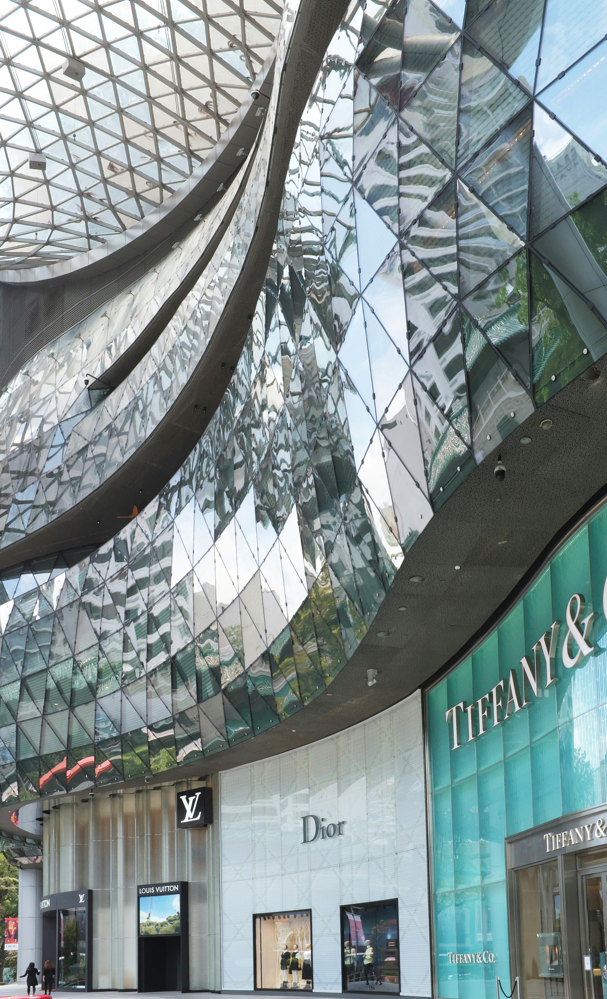 Modern shopping mall with glass facade and luxury storefronts.