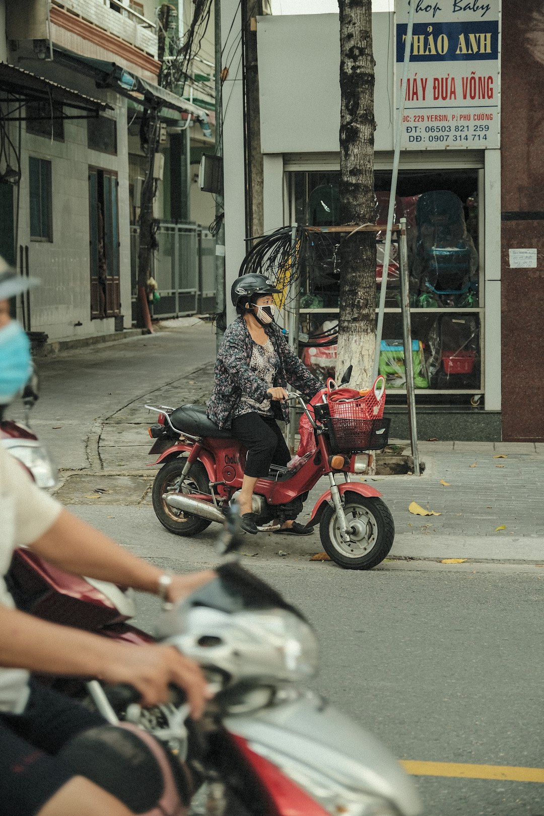 woman in black and white floral dress riding red motorcycle on road during daytime