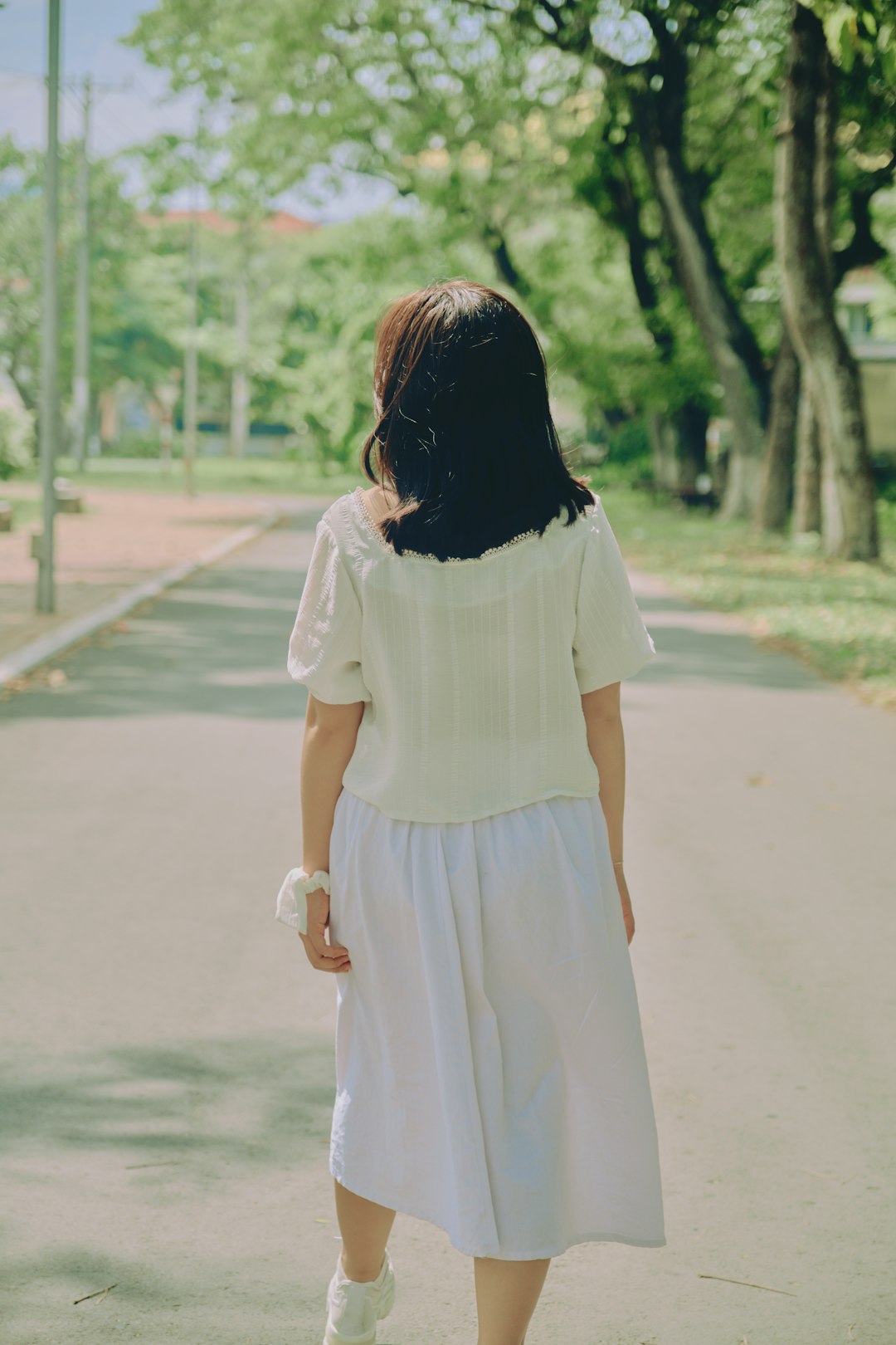 woman in white dress walking on road during daytime