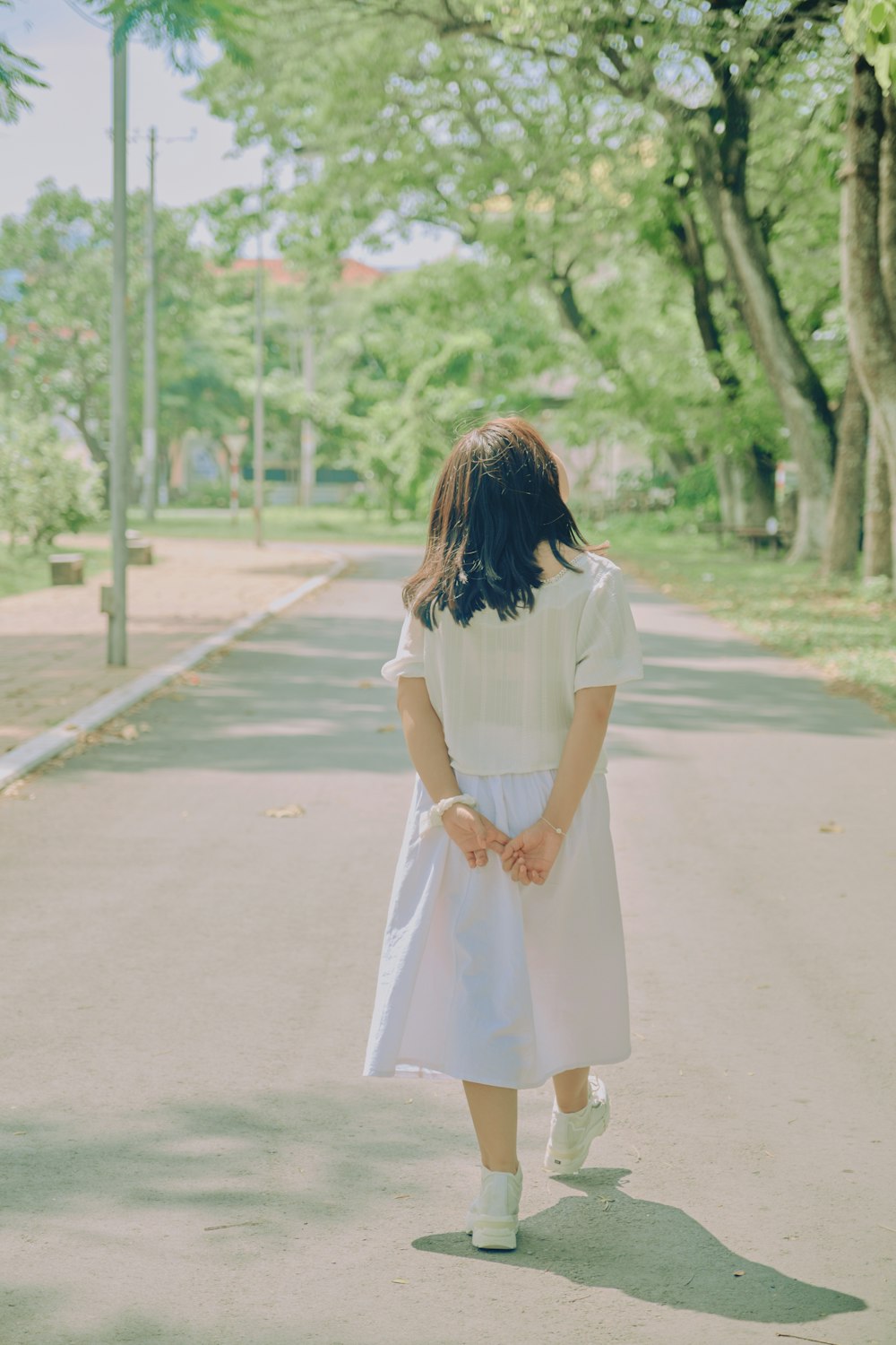 woman in white dress walking on road during daytime