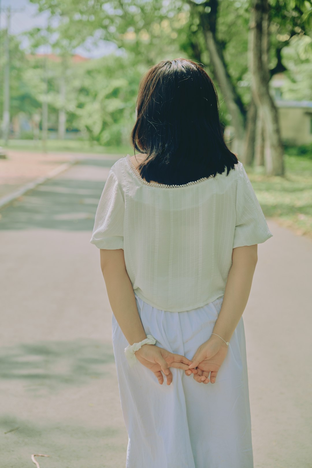 woman in white dress standing on road during daytime