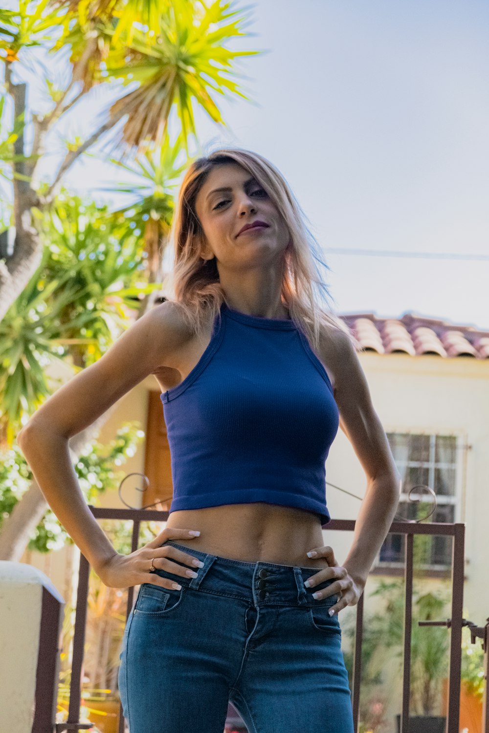 woman in blue tank top and blue denim shorts standing near green plants during daytime